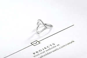 Close-up of minimalist sterling silver hollow heart ring on a white display card