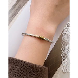 Minimalist 925 sterling silver open bangle featuring a gold smiley face bead charm