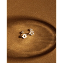 Macro view of minimalist S925 sterling silver flower stud earrings on textured background