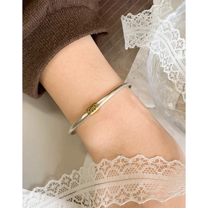 Minimalist 925 sterling silver bangle with a gold smiley face charm on female model