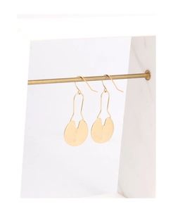 Close-up of golden geometric disc earrings with a brushed metallic finish on a display