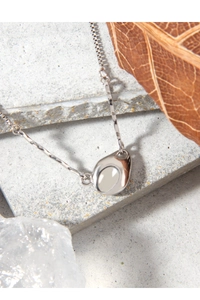 Detailed macro shot of 925 silver geometric teardrop pendant on a textured stone surface
