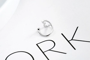 Macro shot of polished silver heart ear cuff on a magazine background for minimalist style