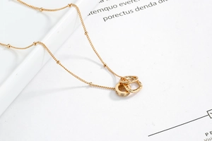 Detailed close-up of double interlocking rings pendant with zircon stones on gold chain