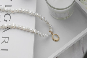 Detail of baroque pearl necklace with a vintage gold oval moonstone pendant on a magazine