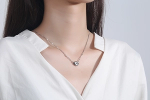 Close-up of minimalist S925 sterling silver bean pendant on a fine box chain necklace