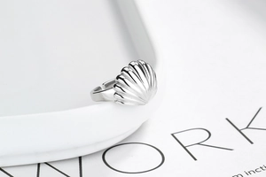 Macro detail of silver S925 shell ring featuring 3D carved radial seashell texture