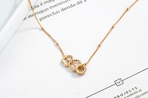 Detailed close-up of 18K gold-plated interlocking triple ring pendant necklace on thin beaded chain