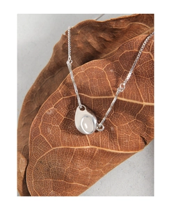 Macro shot of S925 sterling silver box chain necklace with waterdrop pendant on brown leaf