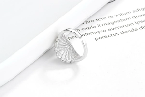 Macro detail of silver S925 shell pattern ring with polished wavy edges and grainy texture