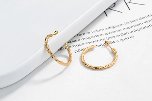 Macro detail of gold irregular textured hoop earrings with hammered lava finish