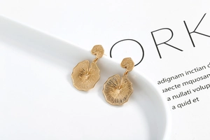 Detailed view of layered golden lotus leaf earrings with fine textured radial patterns