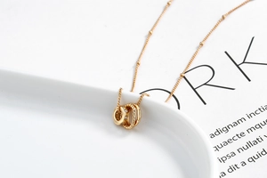 Macro shot of three interlocking rings necklace with beads on chain and gold finish