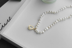 Detailed macro shot of white Baroque pearls and a polished gold oval metal pendant