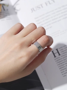 Macro shot of wide silver ring with vertical stripe texture worn on finger over book