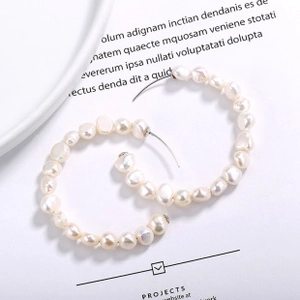 Detailed macro view of large hoop earrings made with natural lustrous baroque pearls