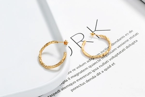 Macro detail of gold irregular lava texture C-shape earrings on a minimalist background