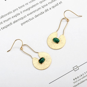 Detail of 18K gold earrings featuring fanned texture and green malachite stone inlay