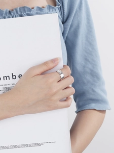 Detailed view of silver wide-band pleated ring with vertical texture on model finger