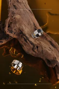 Macro detail of textured silver rings on driftwood with gold reflective background