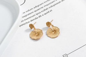 Macro detail of gold leaf-shaped earrings featuring intricate radial vein textures