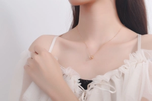 Detail of rose gold geometric interlocking double ring pendant necklace on model