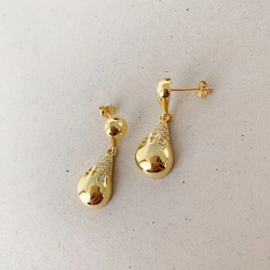 Detail of gold teardrop earrings with fluid metal texture and pave zircon inlay