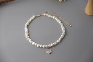 Close-up of natural freshwater pearl necklace with a blue moonstone pendant and gold clasp
