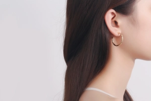 Close-up of gold hoop earrings with hammered texture finish worn by a model