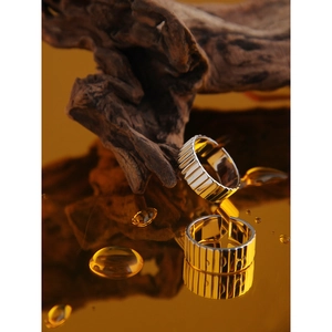 Detailed view of two minimalist S925 silver rings with vertical stripe texture on amber base