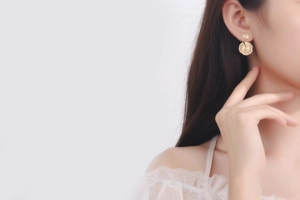 Close-up of gold petal-shaped drop earrings featuring detailed radial textures on a model