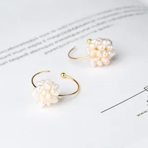 Close-up of elegant gold C-shaped hoop earrings with white pearl clusters on a magazine