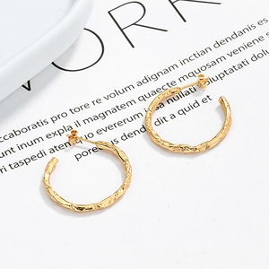Minimalist C-shaped gold hoop earrings with unique lava-like textured organic design