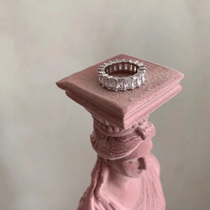 Macro shot of silver eternity ring with emerald cut stones on a pink velvet base