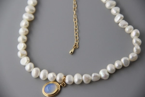 Close-up of Baroque pearl necklace with oval moonstone pendant and gold chain