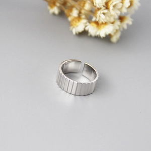 Macro shot of silver ring featuring vertical stripe texture and adjustable open design