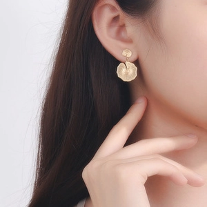 Detail of elegant gold lotus leaf earrings featuring delicate radial veins on matte metal