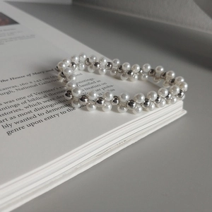 Multilayer woven sterling silver bead bracelet with elegant white pearls on a book