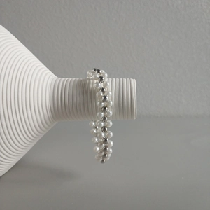 Multilayered sterling silver beaded bracelet with elegant white pearls on a ceramic vase
