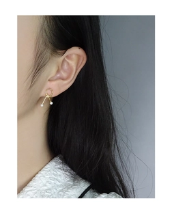 Detail of S925 sterling silver gold knot earrings with delicate white pearls on model