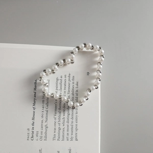 Detail of silver beads and white pearls bracelet elegantly placed on an open book