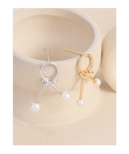 Detailed view of S925 silver knot earrings with double white pearls on ceramic