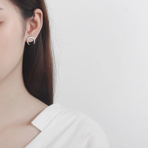Macro close-up of a minimalist S925 sterling silver crescent moon stud earring on an ear