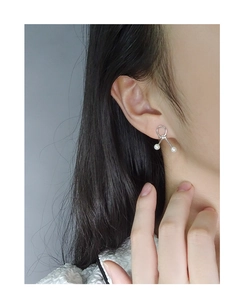 Close-up of S925 sterling silver pearl earrings with minimalist knot design on female model