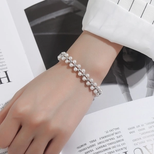 Detail of woven bracelet with white pearls and silver beads on a fashion magazine background