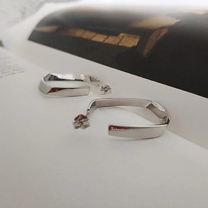 Detailansicht quadratisch gedrehter geometrischer Silberohrringe auf einer Magazinseite