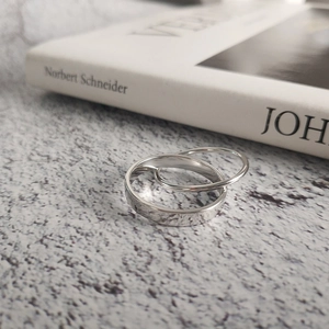 Macro view of polished silver double ring set on minimalist marble and white book background