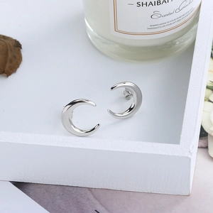 Minimalist S925 sterling silver crescent moon stud earrings on a decorative tray