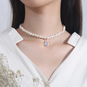 Baroque pearl choker necklace with a gold oval moonstone pendant on a female model