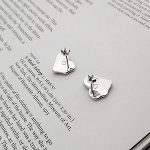 S925 sterling silver heart stud earrings with liquid metal texture on a vintage book
